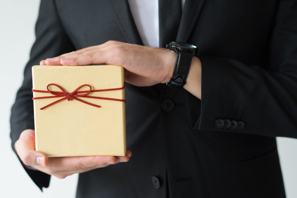 close up man with wristwatch holding gift box