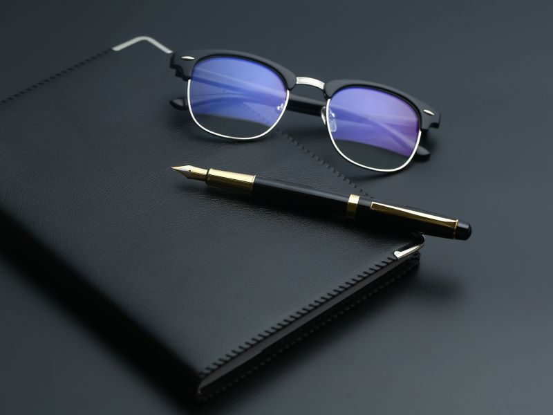 golden pen notebook calculator glasses black desk